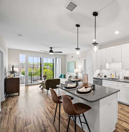 A modern kitchen with white cabinets and a wooden floor.