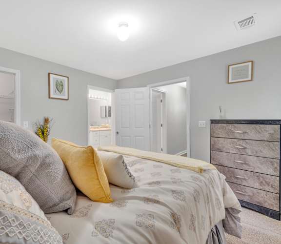 A bedroom with a bed, dresser, and two framed pictures on the wall.