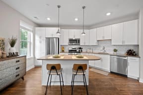 a kitchen with white cabinets and a island with two stools