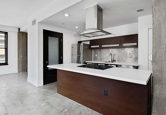 A modern kitchen with a dark wood island and stainless steel appliances.
