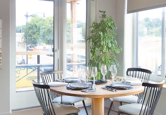 A dining table set with plates and glasses in front of a window.