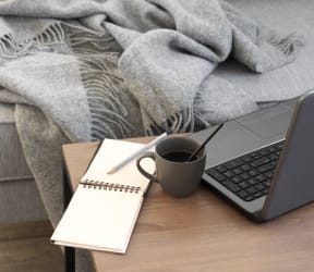 a laptop computer on a desk with a notebook and a cup of coffee