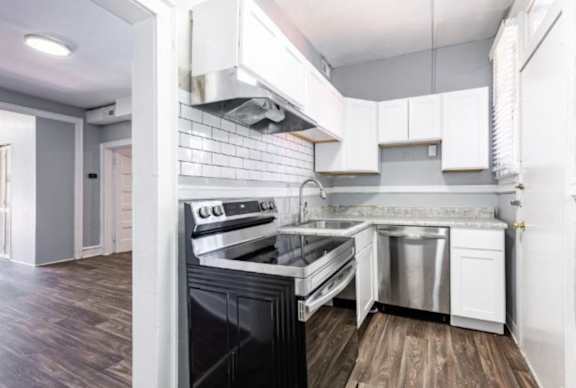 A modern kitchen with a black oven and white cabinets.