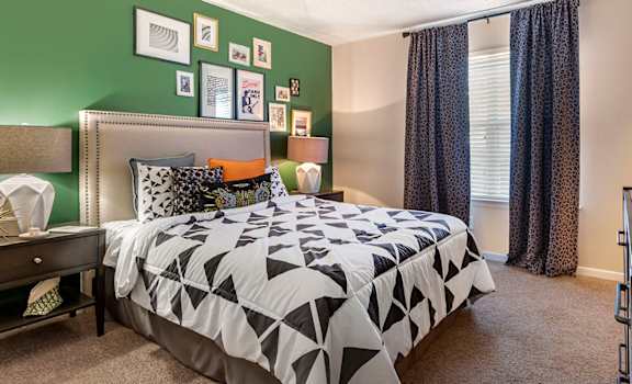 A bedroom with a bed, nightstand, and a green wall.