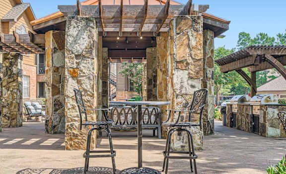 A patio with a table and chairs is surrounded by stone pillars.