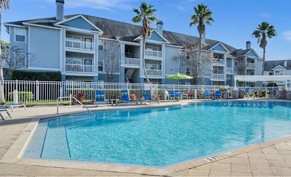 A large swimming pool in front of a building with palm trees.