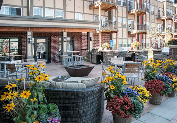 A patio with a table surrounded by chairs and potted plants.