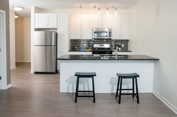 a kitchen with a bar and stools in front of a kitchen counter