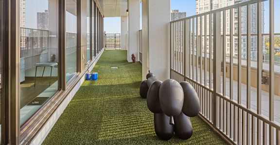 A balcony with a green lawn and a person standing on it.