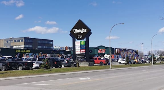 A large sign with C$neijas written on it is in front of a parking lot.