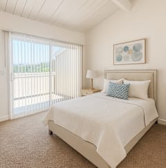 A bedroom with a large bed and a sliding glass door.