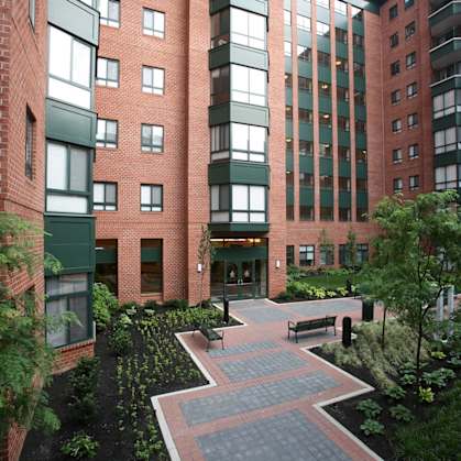 a courtyard with benches and trees in front of a building at Symphony Center Apartments, Baltimore, MD, 21201