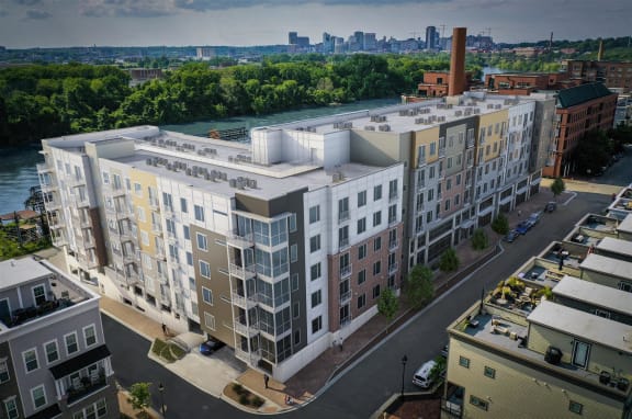 an aerial view of a large apartment building with a river and cityscape in the background at East 51 At Rocketts Landing, Richmond, 23231