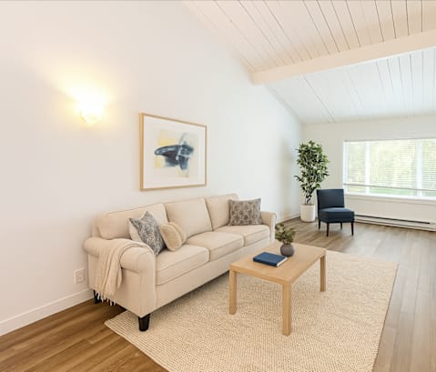 A living room with a couch, a chair, a table, and a painting on the wall.