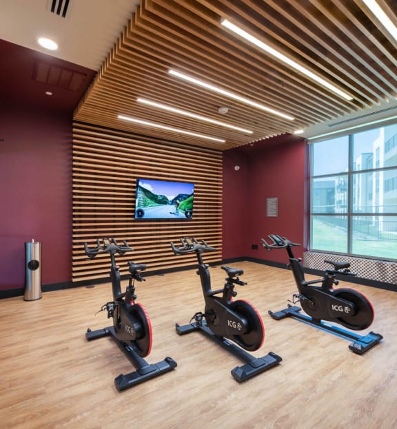 a gym with spin bikes and a tv on the wall