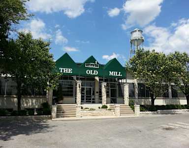The Old Mill building has a green roof and a white water tower in the background.