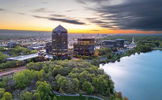 A cityscape with a large building in the center and a body of water in the foreground.
