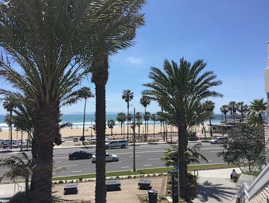 a view of the beach from a hotel balcony with palm trees
