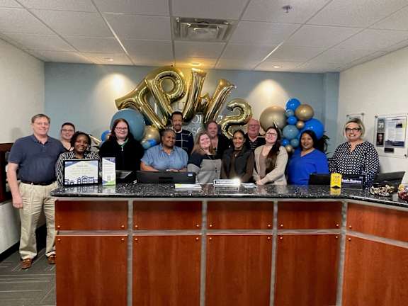 a group of people posing for a photo at the front desk of an office