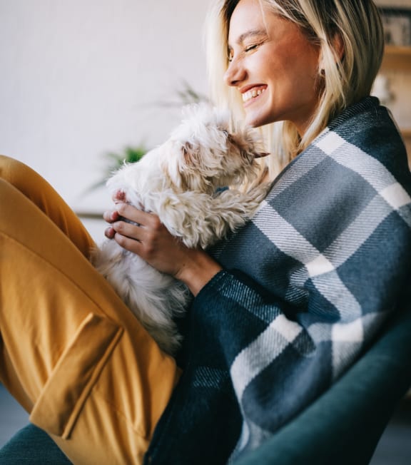 Woman Sitting in Chair Smiling while Holding Dog
