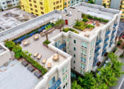 Thumbnail 1 of 22 - A rooftop patio with tables and chairs overlooks a cityscape.