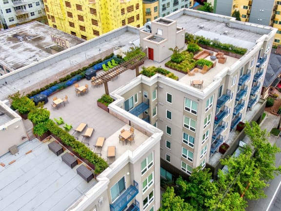 A rooftop patio with tables and chairs overlooks a cityscape.