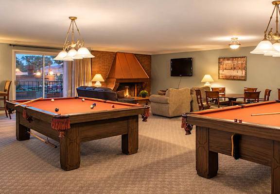 A room with two pool tables and a fireplace.