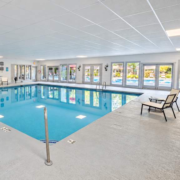 A large indoor swimming pool with lounge chairs and a bench.
