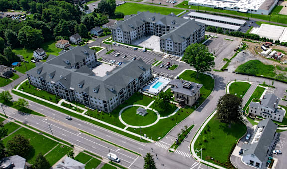 An aerial view of a large building with a pool in the middle of a grassy area.