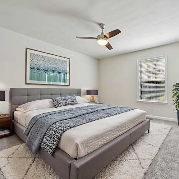 A bedroom with a large bed and a ceiling fan.