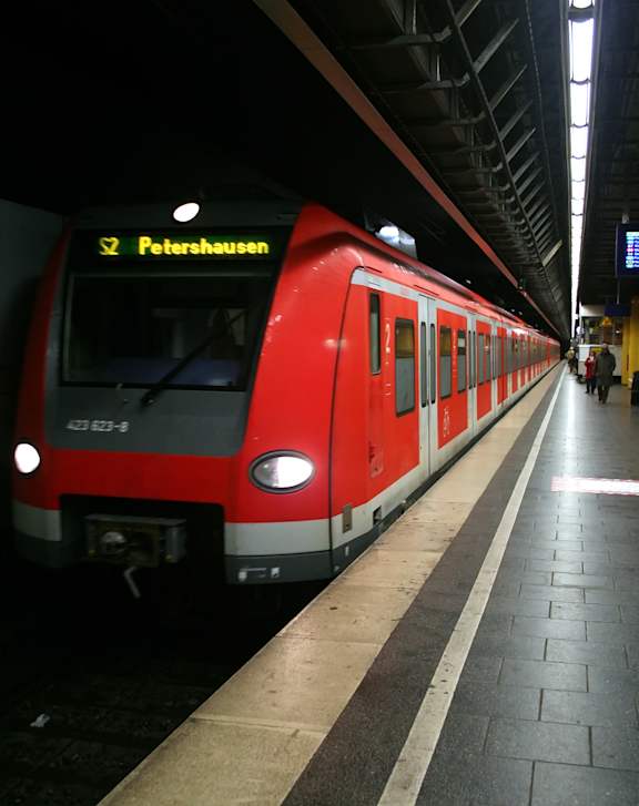 A red train is at the platform of the station.