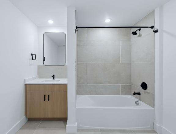 A white bathroom with a sink, mirror, and bathtub.
