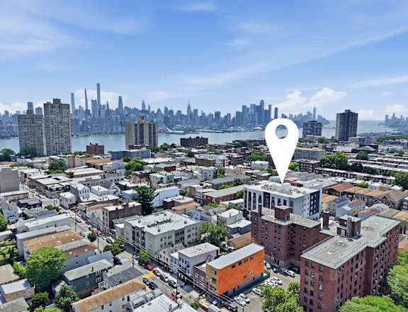A cityscape with a white location marker in the foreground.