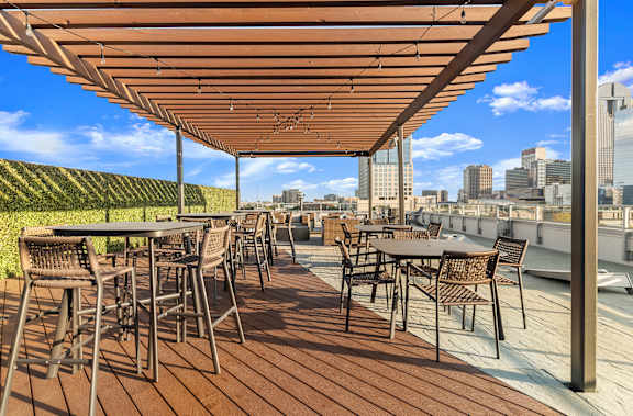 A patio with tables and chairs overlooking a city skyline.