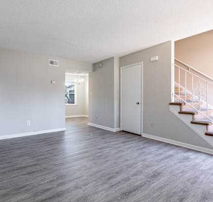 A spacious room with a staircase leading to the second floor.