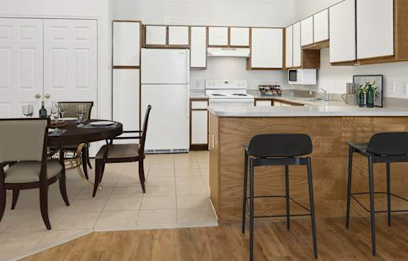 A kitchen with a table and chairs in the foreground and a refrigerator in the background.