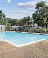 A large outdoor swimming pool surrounded by a fence and trees.