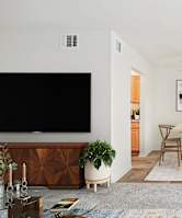 A living room with a television, a dining table, and chairs.