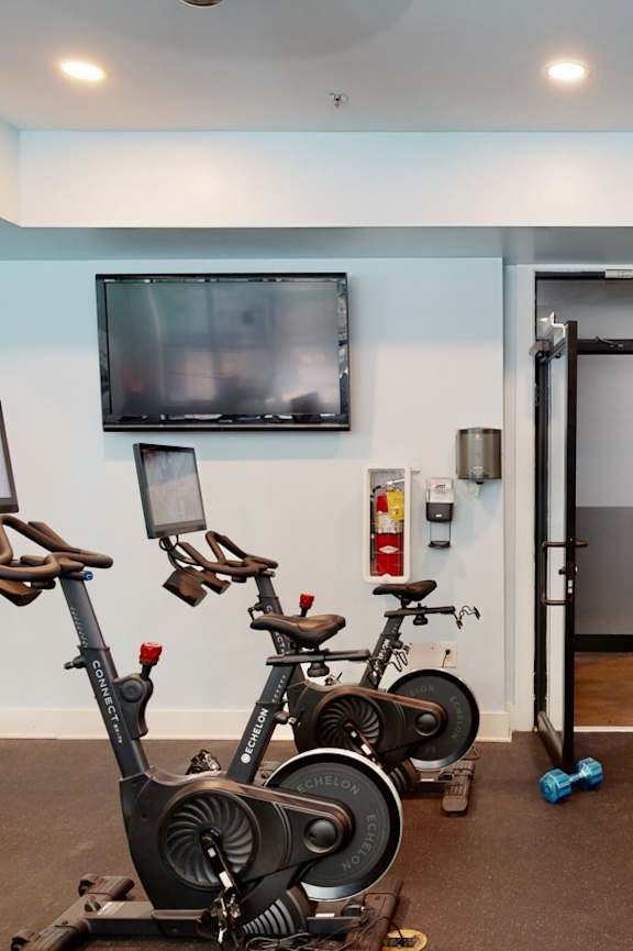 A gym with exercise equipment and a television.