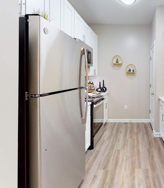 A kitchen with white cabinets and a stainless steel refrigerator.