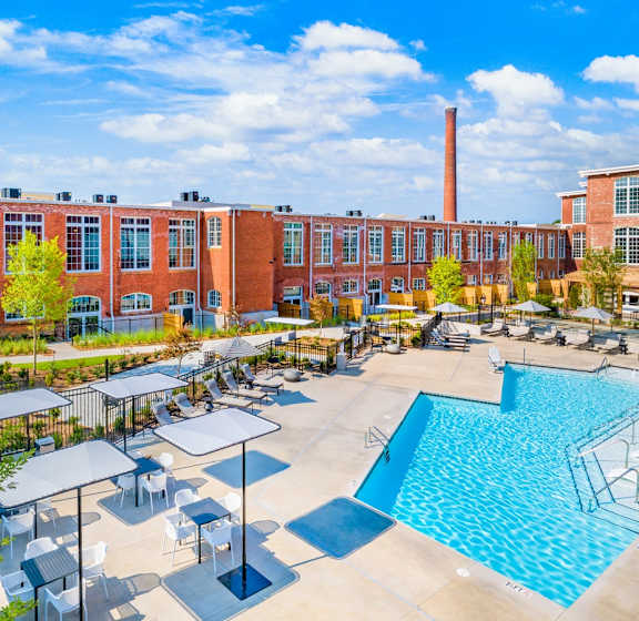 A large swimming pool surrounded by a fence and several lounge chairs at Judson Mill Lofts, Greenville, SC