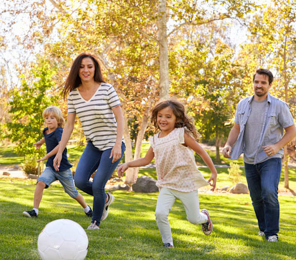 A family playing with a ball in a park.