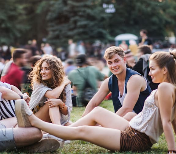 A group of people are sitting on the grass in a park.