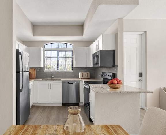 A modern kitchen with white cabinets and a wooden table at San Mareno at Mirasol.
