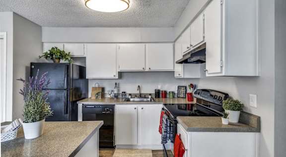 A kitchen with white cabinets and a black fridge.