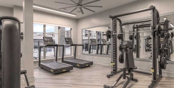 a gym with exercise equipment and a ceiling fan