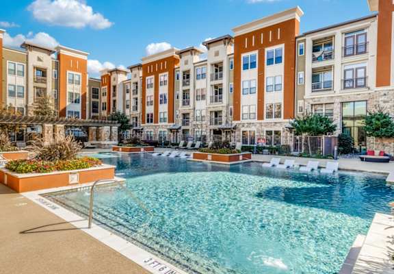 A pool area with chairs and a table.