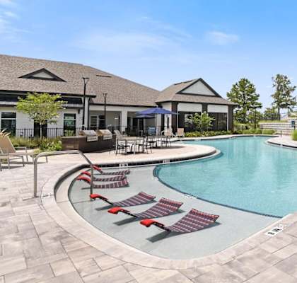 A large outdoor swimming pool surrounded by red lounge chairs.at Century Grove Park, Knightdale North Carolina
