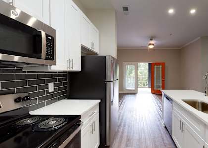 A kitchen with black and white appliances and a red door.