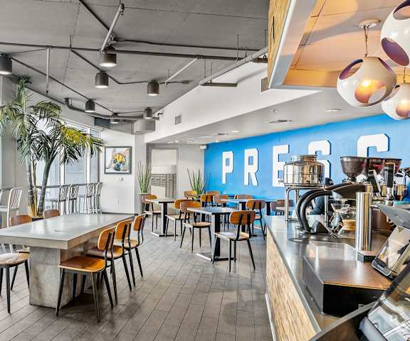 The amazing coffee shop with tables, chairs, a bar with barstools, and a kitchen to make coffee at Skywater at Tempe Town Lake Apartments. 